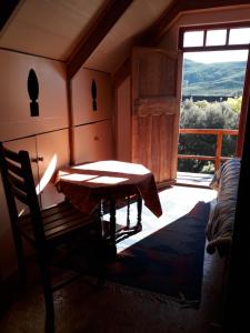 Zimmer mit einem Tisch und einem großen Fenster in der Unterkunft Red Rooster in Barrydale