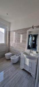 uma casa de banho branca com 2 lavatórios e um espelho em B&B al quadrifoglio posto auto em Trieste