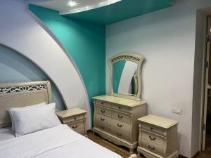 een slaapkamer met een bed, 2 dressoires en een spiegel bij ZahroSulton in Samarkand