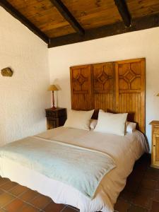 um quarto com uma cama grande e uma cabeceira em madeira em La casita del hortelano em Robledo de Chavela