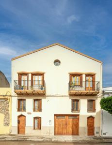 un edificio blanco con puertas y ventanas de madera en Casa Rural l'Olivera en Sant Mateu, cerca de Morella y Peñíscola - Casa Completa - Mínimo 2 noches en Sant Mateu