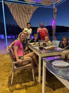 Nile View Guest House في أسوان: مجموعة من الناس يجلسون على طاولة على الشاطئ