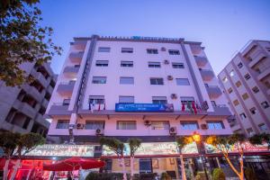een hoog wit gebouw met bomen ervoor bij Appart Hotel Star in Tanger