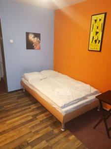 Cama en habitación con pared de color naranja en Hotel Praha Club bed & breakfast, en Praga