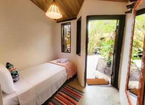 1 dormitorio con 1 cama y puerta a un patio en Pousada Raiz Forte, en Caraíva