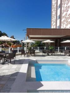 - une piscine avec des tables, des chaises et des parasols dans l'établissement Spazzio diRoma acesso diRoma Acqua Park gratuito Star Temporada, à Caldas Novas