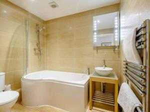 a bathroom with a tub and a sink and a toilet at The beautifully central Flat 3 The Cobourg Tenby in Pembrokeshire