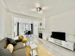 a living room with a couch and a television at Modern 4 Bed Romford Home - Free Parking in Great Warley Street