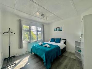 a bedroom with a bed with blue sheets and a window at Modern 4 Bed Romford Home - Free Parking in Great Warley Street