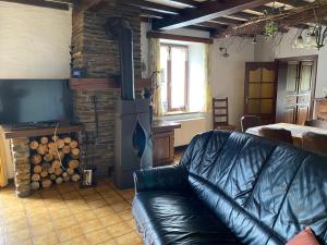 ein Wohnzimmer mit einem Ledersofa und einem Holzofen in der Unterkunft Quiétude à la ferme in Houdremont