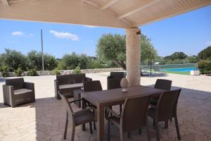 eine Terrasse mit einem Tisch, Stühlen und einem Pool in der Unterkunft Dimora Sasa in Putignano