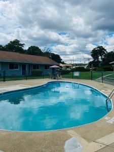 uma grande piscina azul em frente a uma casa em Captain's Lodge Motel em Gloucester