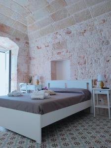 um quarto com uma cama branca e uma parede de tijolos em Dimora Storica Il Tiglio em Castellana Grotte