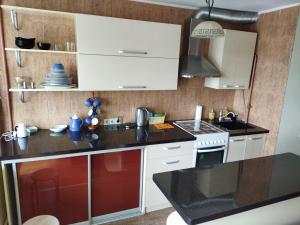 a kitchen with white cabinets and a black counter top at Itaja Apartment 91 in Šiauliai