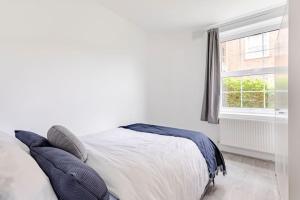 ein Schlafzimmer mit einem Bett mit Kissen und einem Fenster in der Unterkunft Lovely 3 bedroom flat in North London in London