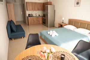 a room with a bed and a table and a kitchen at Anesis Airport rooms 204 in Koropíon