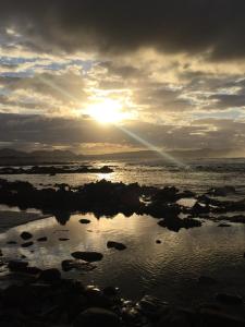 un coucher de soleil sur une étendue d'eau avec des rochers dans l'établissement Paradise@Pearly, à Pearly Beach