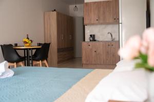 a room with a kitchen and a table with chairs at Anesis Airport rooms 204 in Koropíon
