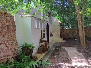 a white house with a staircase and trees at Manta Cottage - Forest view in Galu