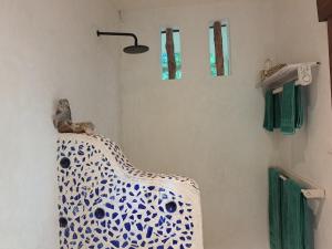 een badkamer met een blauwe en witte wastafel bij Manta Cottage - Forest view in Galu