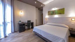 1 dormitorio con cama blanca, escritorio y ventana en CH Hotel San Silvestro, en San Prospero 