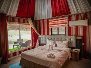 a bedroom with a bed with red curtains and a window at Mouna Luxury Rum Camp in Wadi Rum