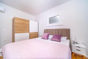 a bedroom with a large white bed with purple pillows at Spacious one bedroom apartment Lana in Postira