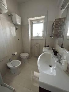 ein weißes Bad mit einem WC und einem Waschbecken in der Unterkunft Tiberia Apartment in Rom