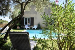 a swimming pool in a yard with a chair at Jolie maison au pied du Luberon in Cucuron