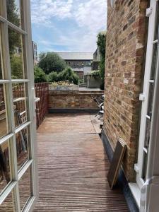 Une porte ouverte s'ouvre sur une terrasse dotée d'un mur en briques. dans l'établissement Quiet and cozy 2 SEPERATE BEDROOMS and 2 BATHROOM with terrace, à Londres