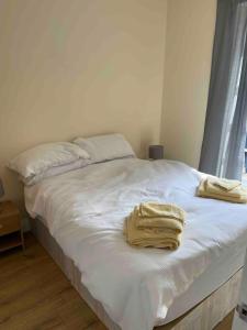 - un lit blanc avec 2 serviettes dans l'établissement Quiet and cozy 2 SEPERATE BEDROOMS and 2 BATHROOM with terrace, à Londres