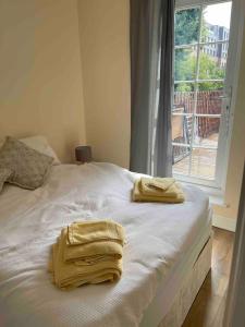 two towels on a white bed with a window at Quiet and cozy 2 SEPERATE BEDROOMS and 2 BATHROOM with terrace in London