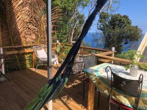 a hammock on a deck with a table and chairs at Bungalow 4 épices in Saint-Leu