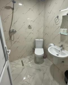 a white bathroom with a toilet and a sink at Hotel Mogzauri, Khulo in Khulo