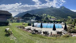 a swimming pool with chairs and umbrellas in a yard at Hotel Senningerbräu in Bramberg am Wildkogel