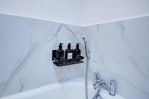 a bathroom with a shelf with bottles on the tub at Stylish Apt with Balcony and easy central access in London