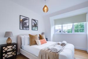 a white bedroom with a bed with towels on it at Stylish Apt with Balcony and easy central access in London