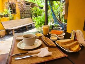 a table with a tray of breakfast foods and a cup of coffee at Pousada Raiz Forte in Caraíva