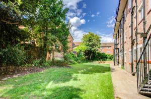 an alley between two brick buildings with grass at Stylish Apt with Balcony and easy central access in London