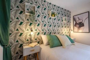 a bedroom with a large bed with a leafy wall at Esope by Kleidos-Ravissant T2 en plein centre de Château-Thierry in Château-Thierry