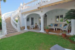 a white house with a patio with a table and chairs at Villa Renoir in Oliva