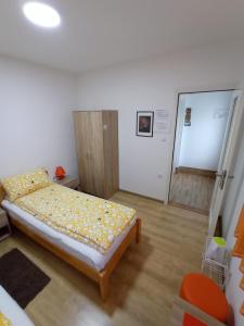 een kleine slaapkamer met een bed met gele lakens en een deur bij Sobe Ana in Sombor