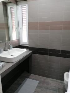 La salle de bains est pourvue d'un lavabo, d'un miroir et de toilettes. dans l'établissement Gemelli Torrevecchia Apartment, à Rome