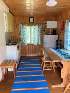 eine kleine Küche mit einem Tisch und einem blauen Teppich in der Unterkunft Lappalaisen lomamökit Pihamökki in Puumala