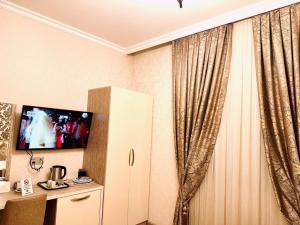 une chambre avec une télévision et un rideau dans l'établissement Sebail Inn Hotel, à Baku