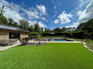 um quintal com piscina e relva verde em La villa d'Eva em Léguillac-de-Lauche