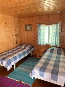 two beds in a wooden room with a window at Lappalaisen lomamökit Pihamökki in Puumala