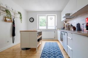 a kitchen with white cabinets and a blue rug at Modernes Zuhause - Küche - Top Anbindung - High WLAN in Holzwickede