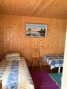 a room with two beds and a chair in a cabin at Lappalaisen lomamökit Pihamökki in Puumala