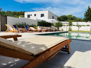 a swimming pool with lounge chairs and a bed next to a pool at Villa Felix in Murter